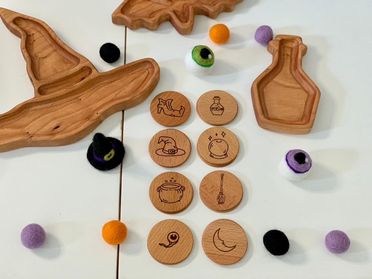 Hand drawn witchy magic memory game wooden tokens with engraved magical icons and felt eyeballs on white surface