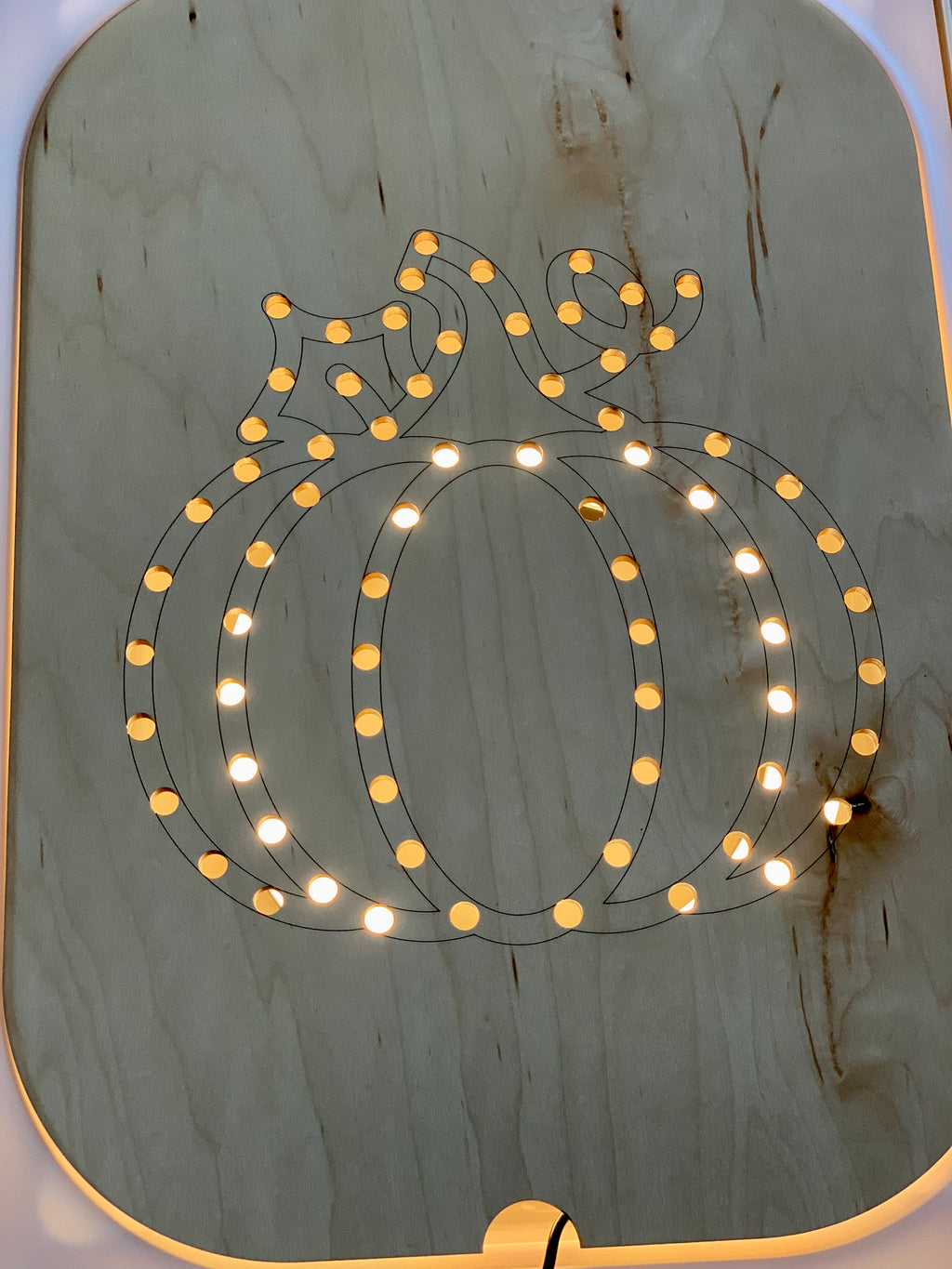 Light up wooden pumpkin-shaped Flisat insert with small round holes illuminated by warm white lights on light wood background