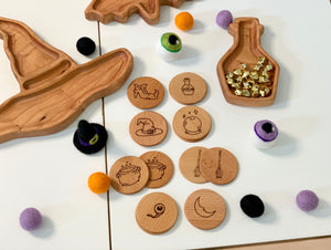 Hand drawn wooden witchy magic memory game pieces with engraved mystical symbols and colorful felt balls on white surface