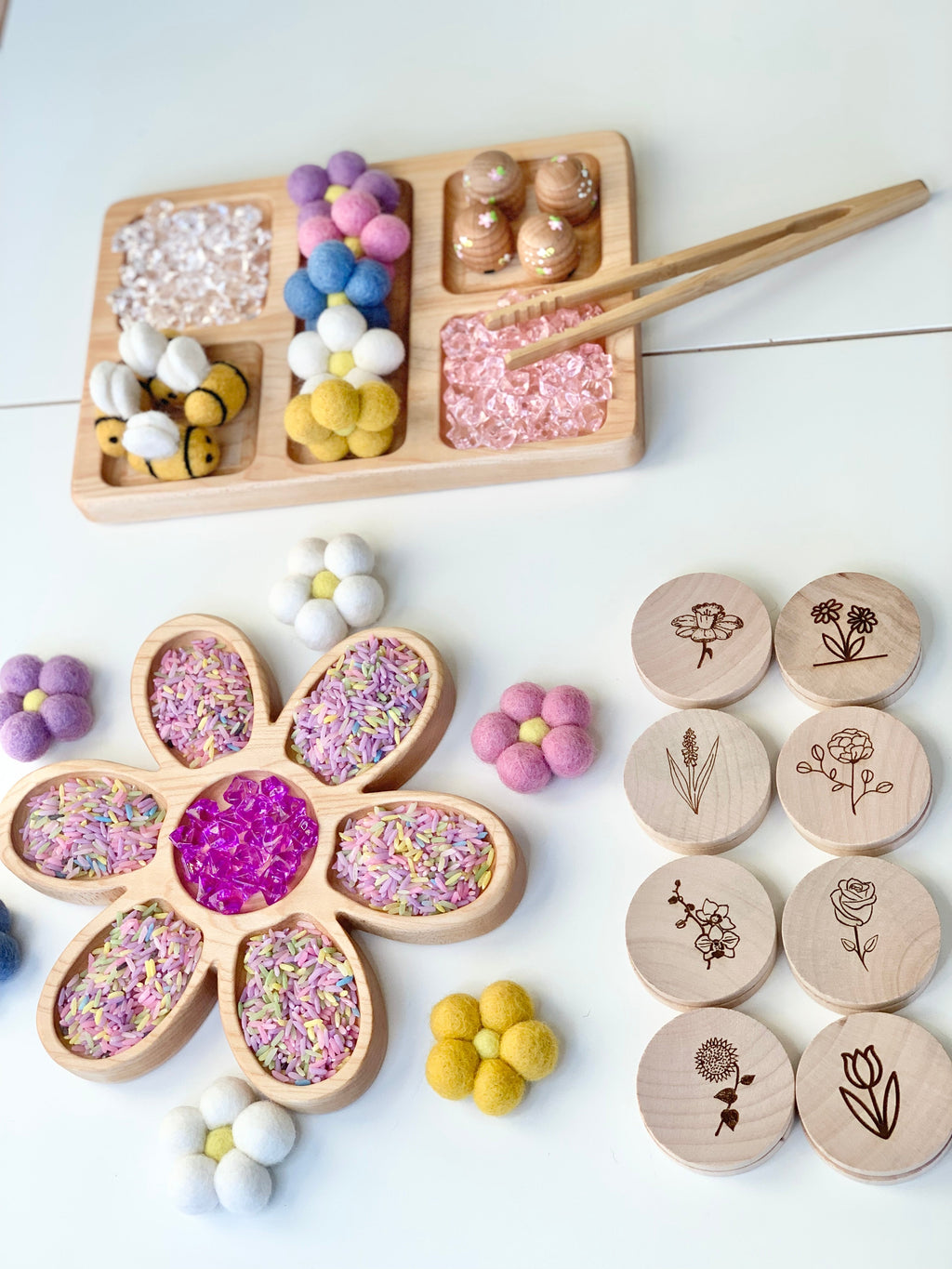 Wooden flower tray filled with colored rice and beads, wooden tokens with botanical engravings, and felt flower decorations