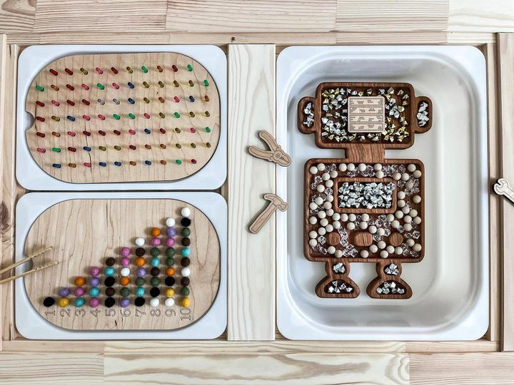 Wooden robot-shaped sensory tray with wooden pegboard, colorful beads, and sorting trays on natural wood surface