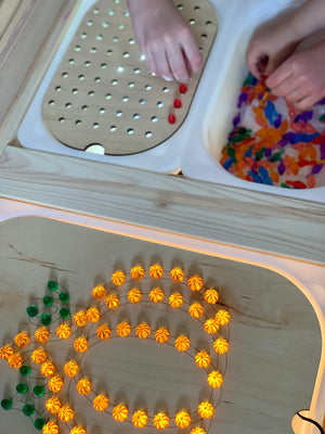 Light up pumpkin-shaped Flisat insert with glowing orange pegs and children playing with colorful sensory materials nearby