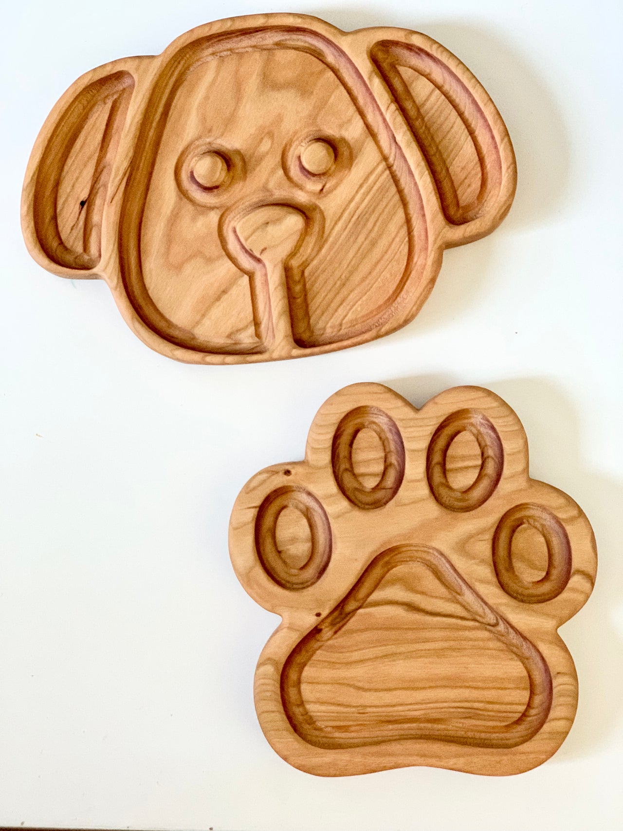 Wooden puppy dog face plate and paw-shaped sensory tray with carved compartments on white surface