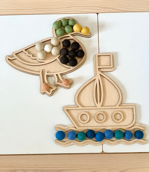 Fillable duck and boat play trays with colorful felt balls on light wood and white surface