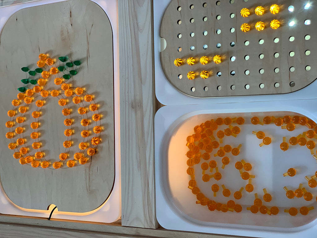 Wooden pumpkin-shaped Flisat insert with orange and green light pegs on white table surface