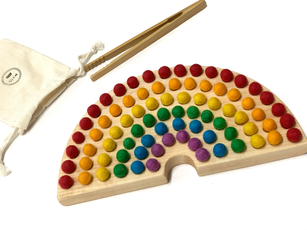 Canadian cherry hardwood rainbow sorting board with colorful felt balls and wooden tweezers on white background