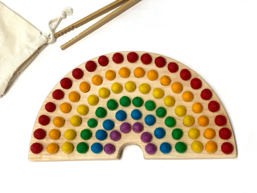 Canadian cherry hardwood rainbow sorting board with smooth engraved holes and colorful felt balls on white background