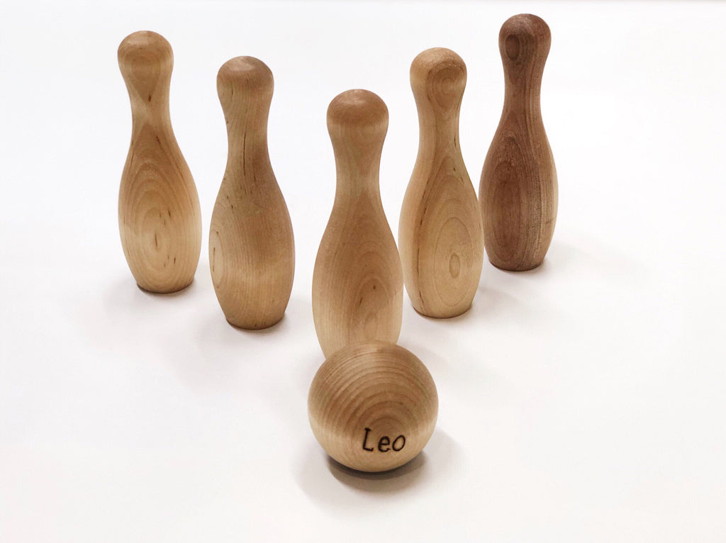 Natural wood toddler bowling set with six pins and a personalized ball engraved with the name Leo.