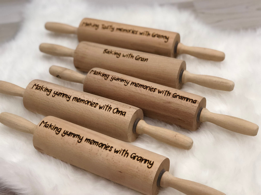 Five personalized wooden rolling pins with custom engraved messages on natural wood background
