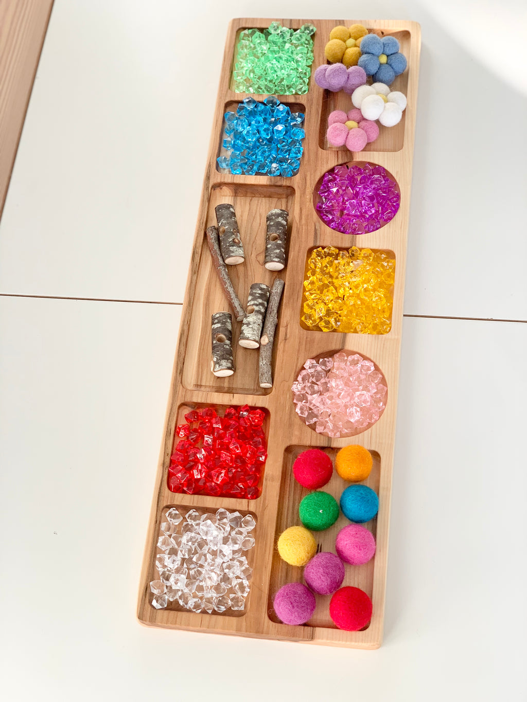 Extra large natural wooden tinker tray with colorful sensory items including pom poms, sticks, and translucent beads
