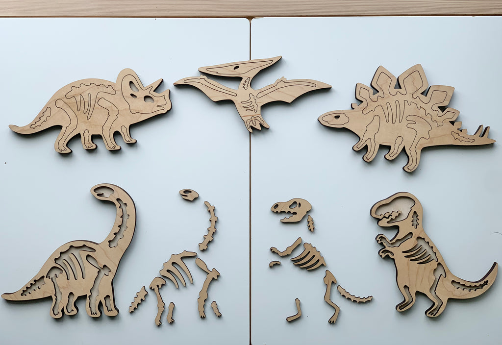 Wooden dinosaur skeleton puzzles featuring Triceratops, Pterodactyl, Stegosaurus, Brachiosaurus, Velociraptor, and T-Rex on white surface