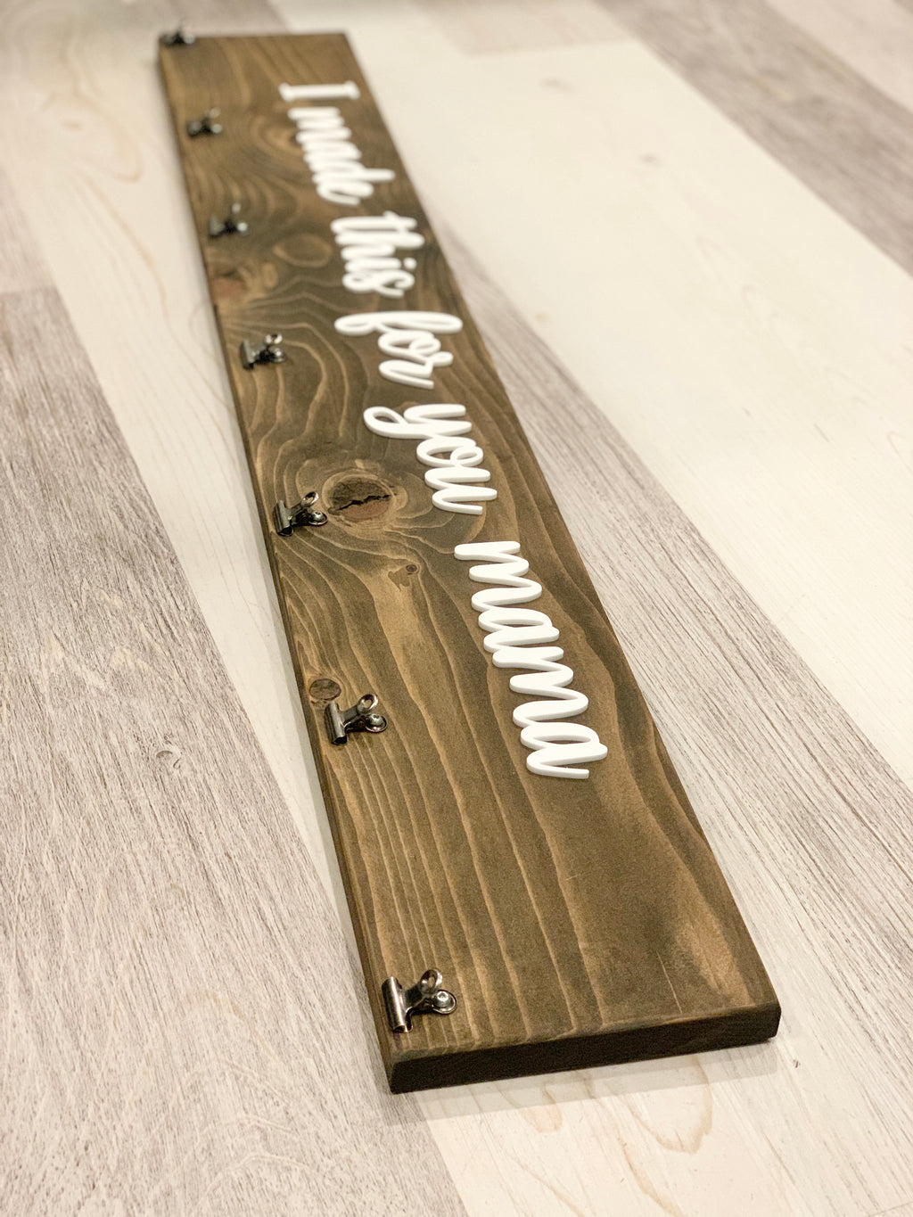 Dark stained wooden display sign with white cursive letters reading I made this for you mama and clips for children's artwork