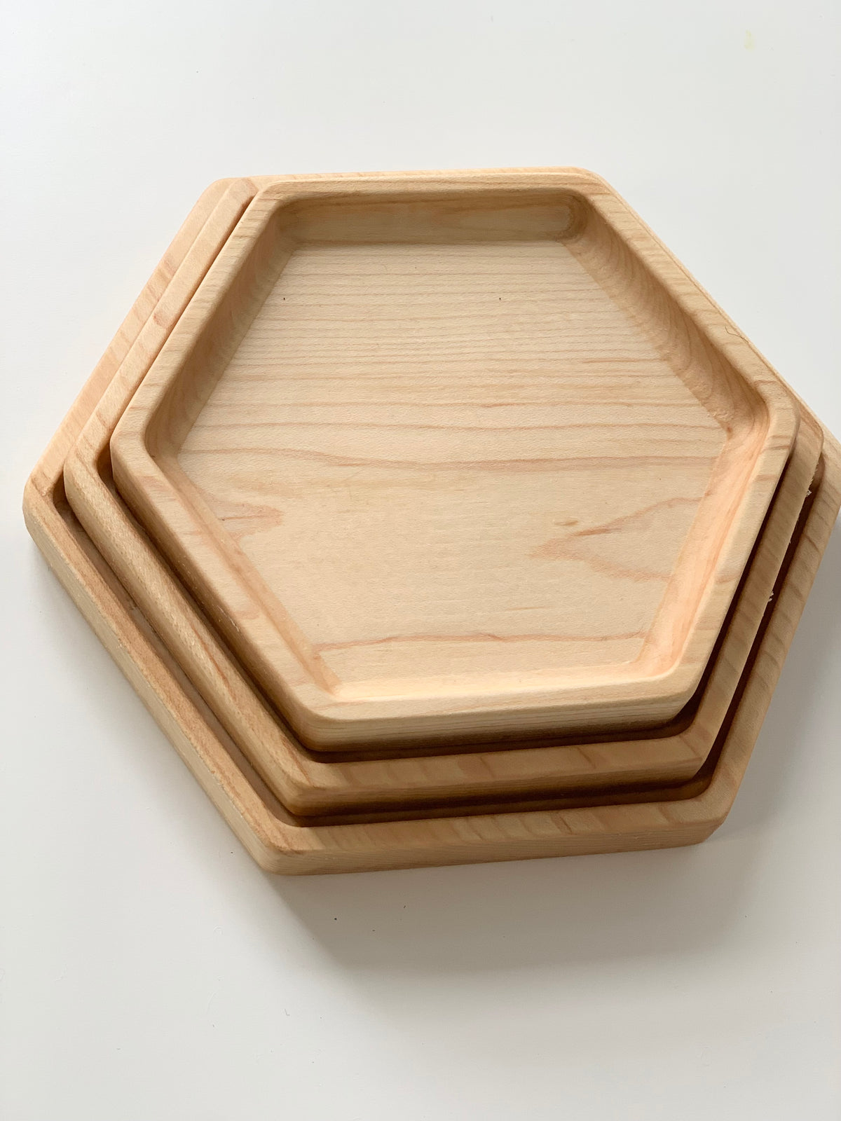 Set of three natural wood nesting hexagon plates with smooth edges on white background