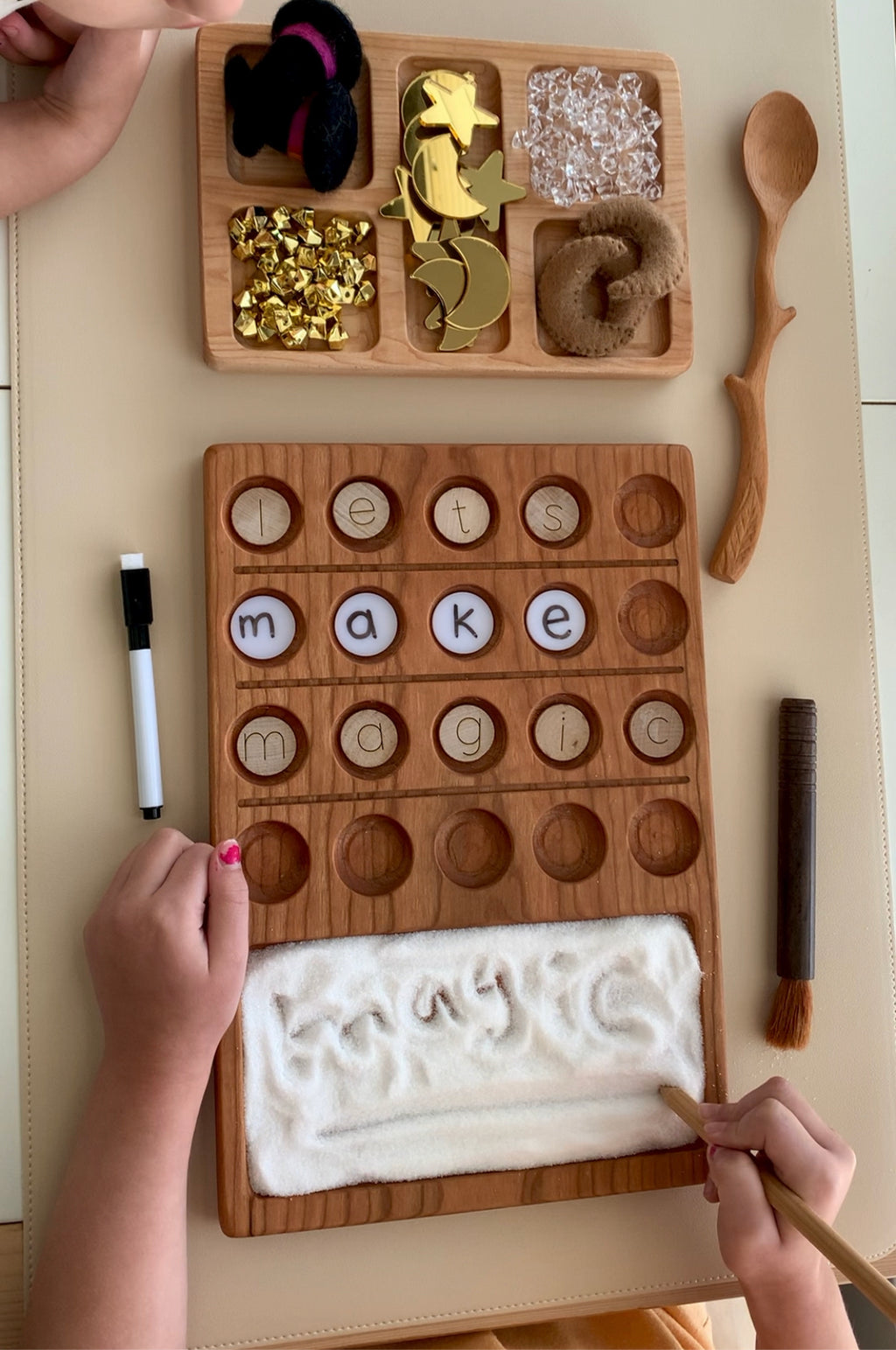 Wooden 20 frame sensory tray with letter discs, salt tray for writing, wooden spoon, dry erase pen, and sensory objects on beige surface