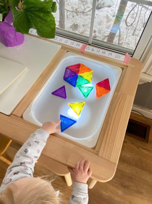 Small wooden Flisat table with frosted acrylic insert and colorful translucent geometric shapes on lighted surface