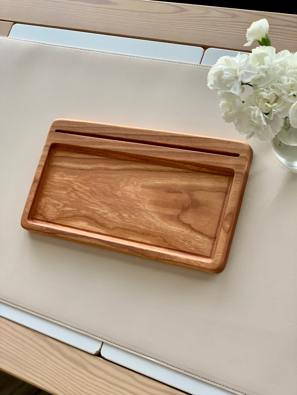 Rectangular wooden writing tray with smooth finish and groove for flashcards, on light beige surface next to white flowers