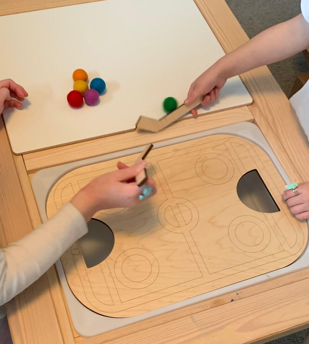 Children playing with wooden table top hockey Flisat insert and colorful felt balls on wood table