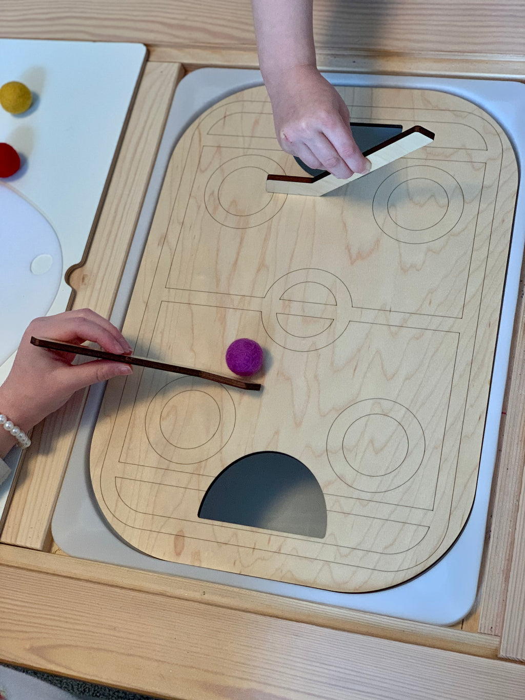 Wooden table top hockey Flisat insert with two hockey sticks and felt balls on wooden surface