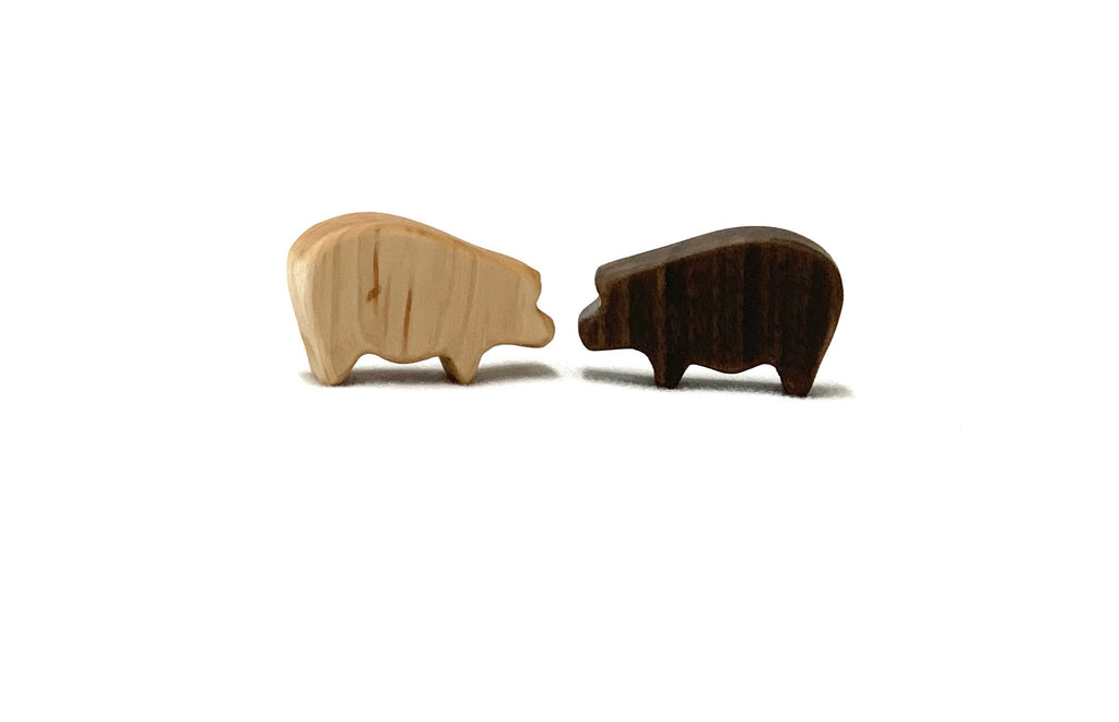 Two small wooden farm animal toy figurines, one light and one dark, on white background