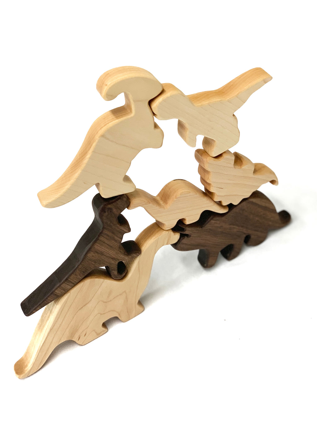 Set of natural and dark wood dinosaur toy figurines stacked in balancing arrangement on white background