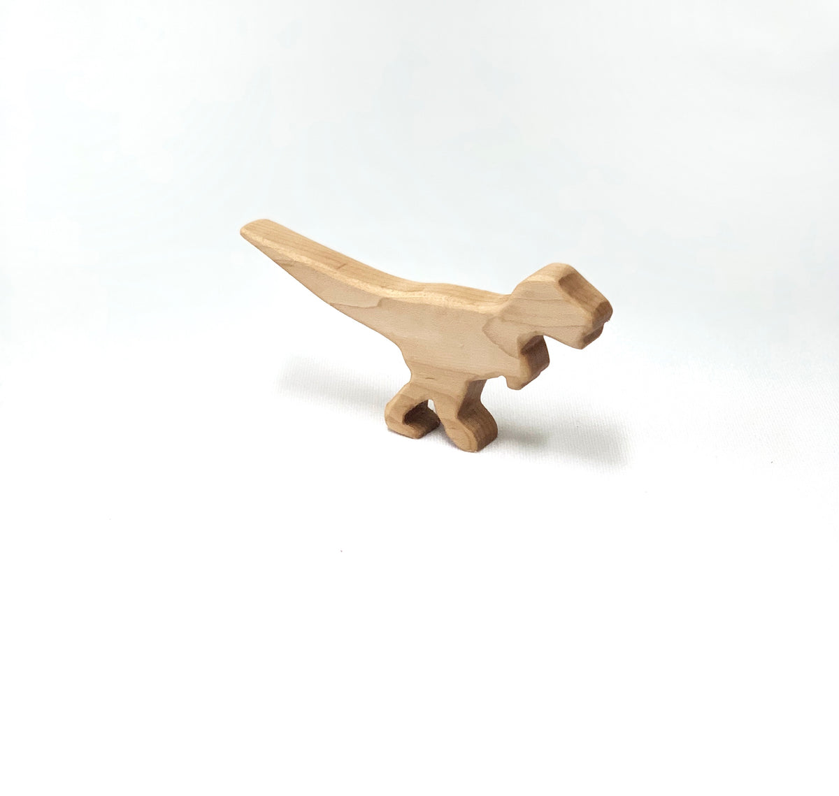 Small natural wooden T Rex dinosaur toy figurine with smooth edges on white background
