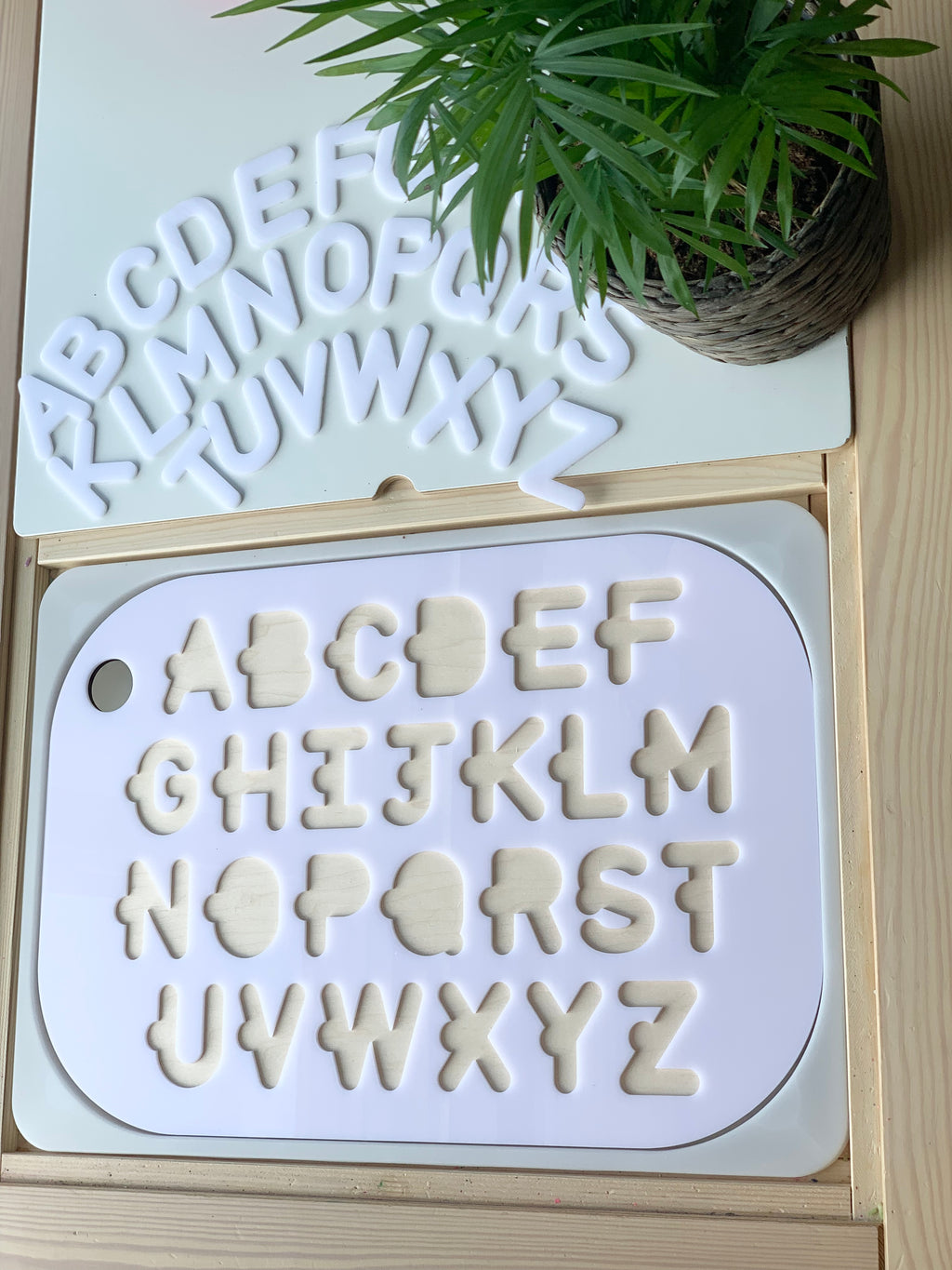 Uppercase alphabet puzzle with white acrylic letters and maple plywood base in a Flisat table top insert with plant on wood surface
