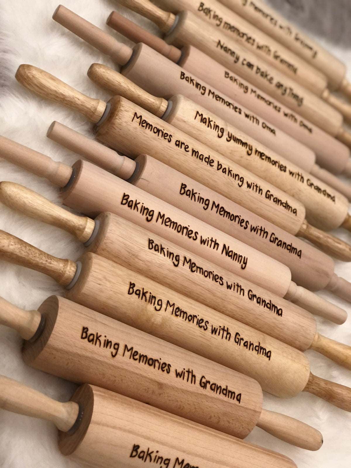 Collection of personalized wooden rolling pins with custom engraved baking messages on light wood background