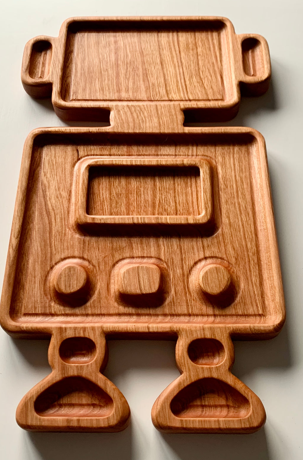 Wooden robot-shaped sensory tray with carved body, arms, legs, and screen details on a light surface