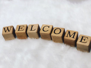 Custom 2-inch wooden blocks spelling the word WELCOME on a soft white surface background