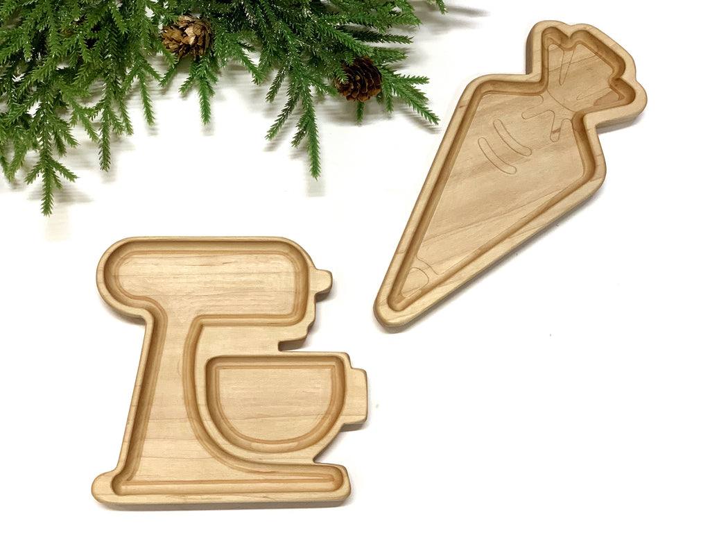 Natural wood sensory trays shaped like a stand mixer and a carrot on white background with pine branches nearby