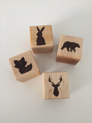 Four 2-inch custom wood blocks with engraved animal silhouettes including a rabbit, bear, fox, and deer head