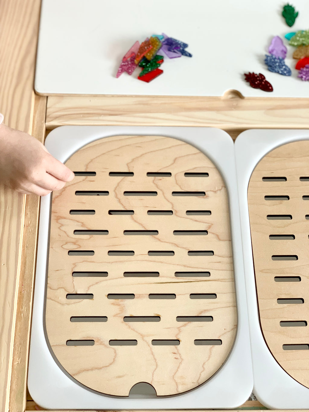 Flisat table top insert with wooden slots sorter showing small bin size and child's hand placing item into slot