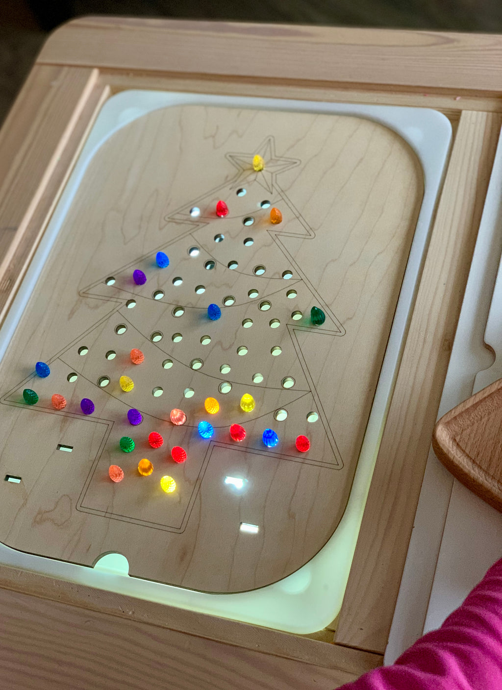 Wooden Flisat Christmas tree insert with colorful light-up pegs fitted into holes on lighted base tray