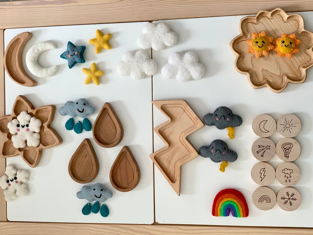 Wooden weather memory game pieces including felt clouds, stars, raindrops, lightning bolt, sun, moon, rainbow, and wooden discs with weather icons