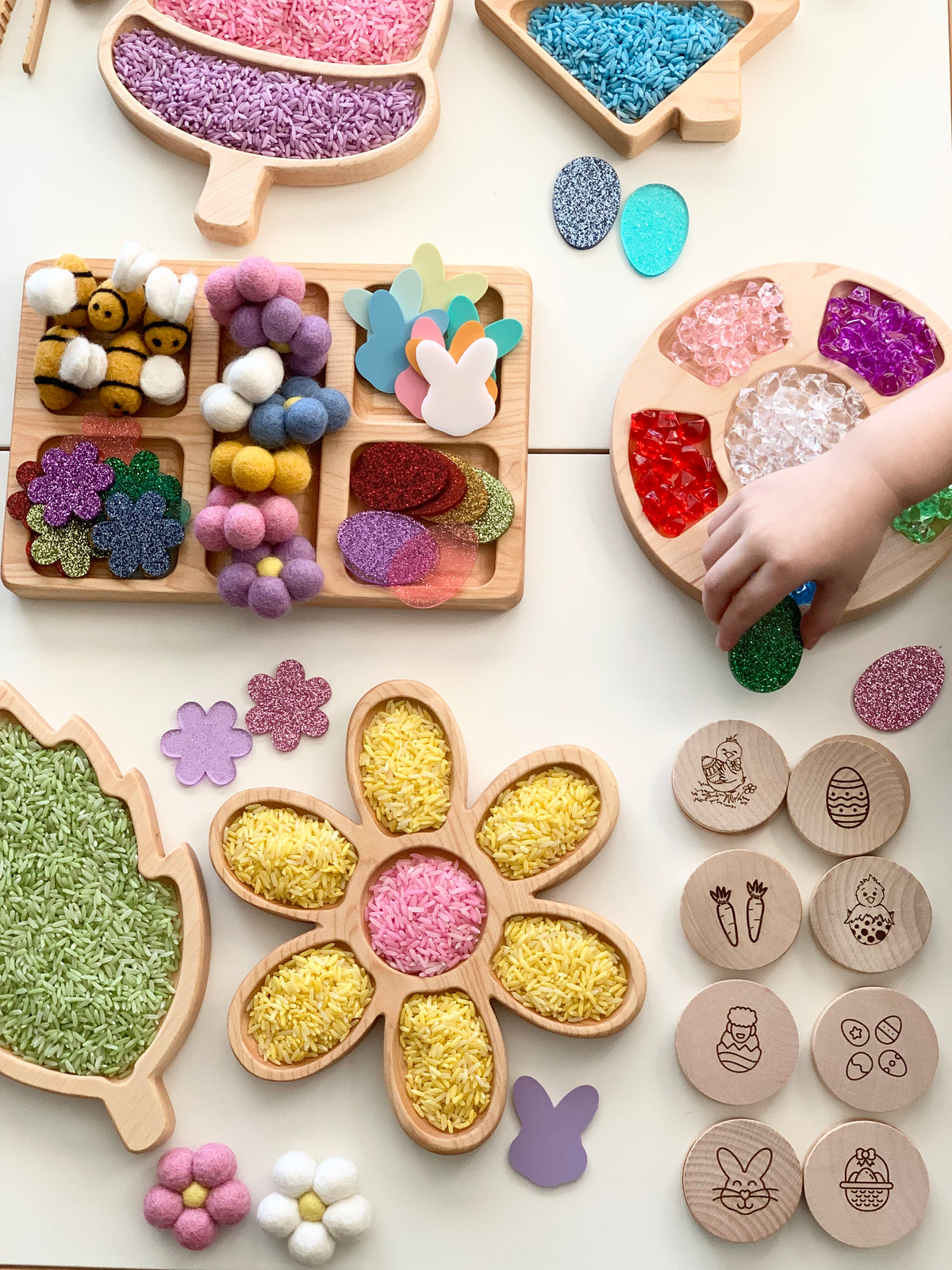 Wooden Easter memory game pieces with engraved holiday icons arranged near colorful textured craft materials in wooden trays