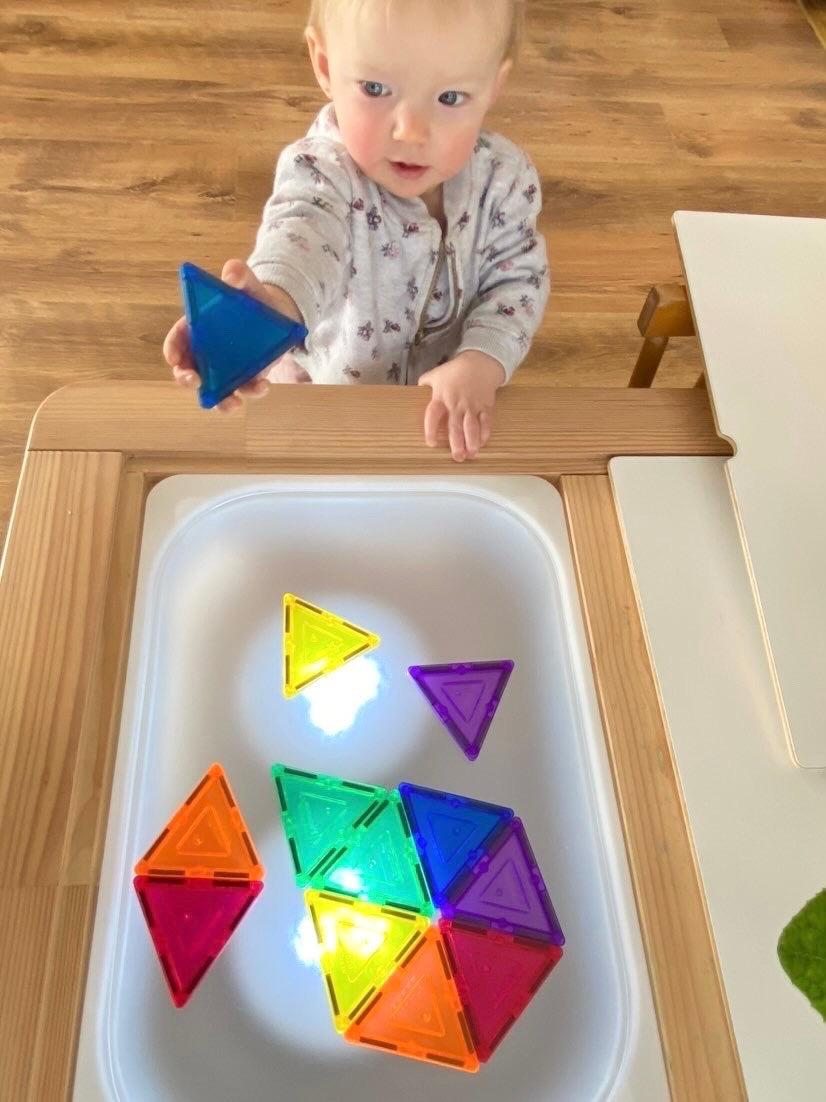 Child playing with colored translucent magnetic tiles on frosted acrylic Flisat tabletop light table with wood frame