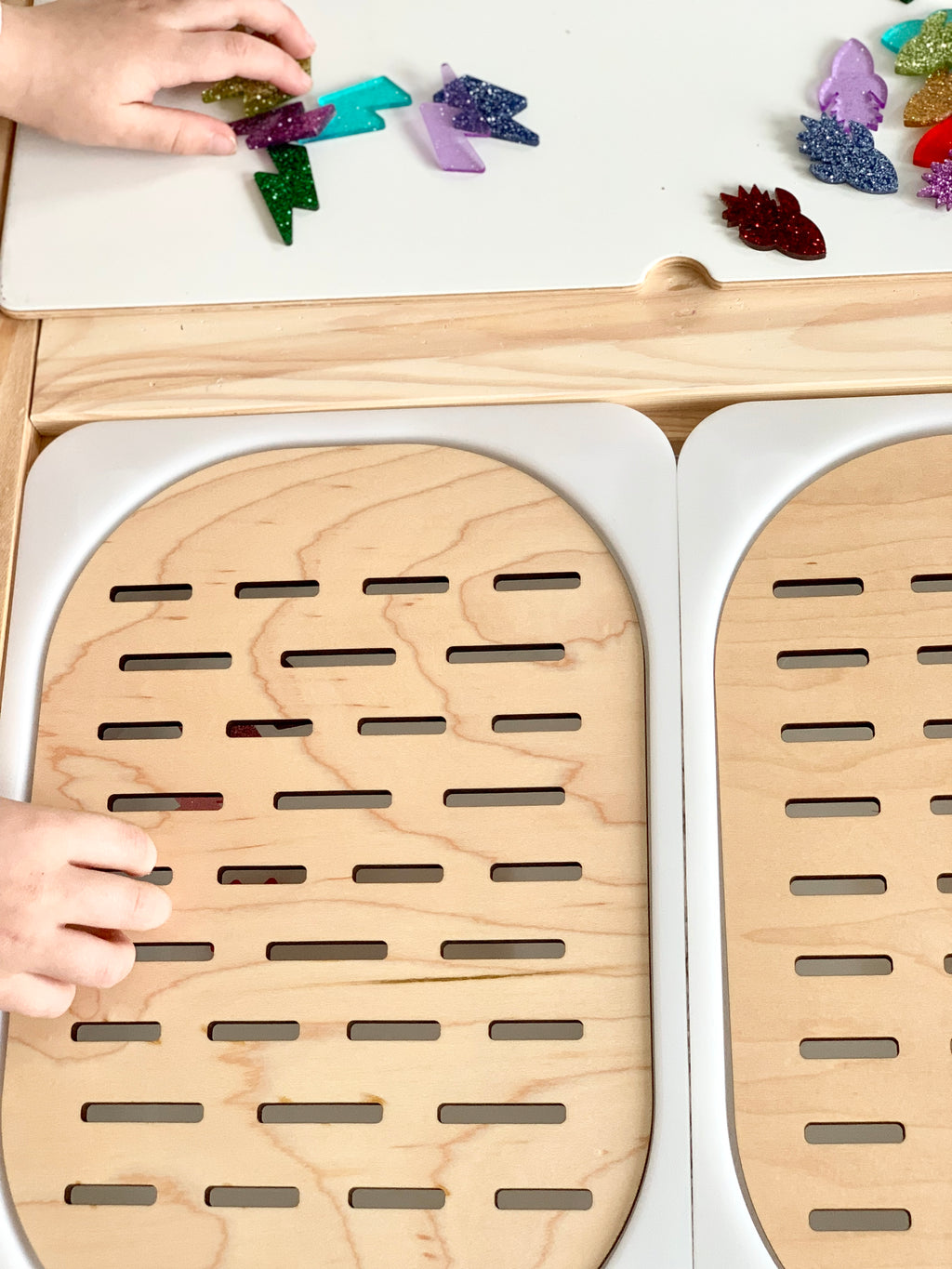 Wooden Slots Sorter Flisat table top insert with small slot openings and children's hands placing colorful resin shapes