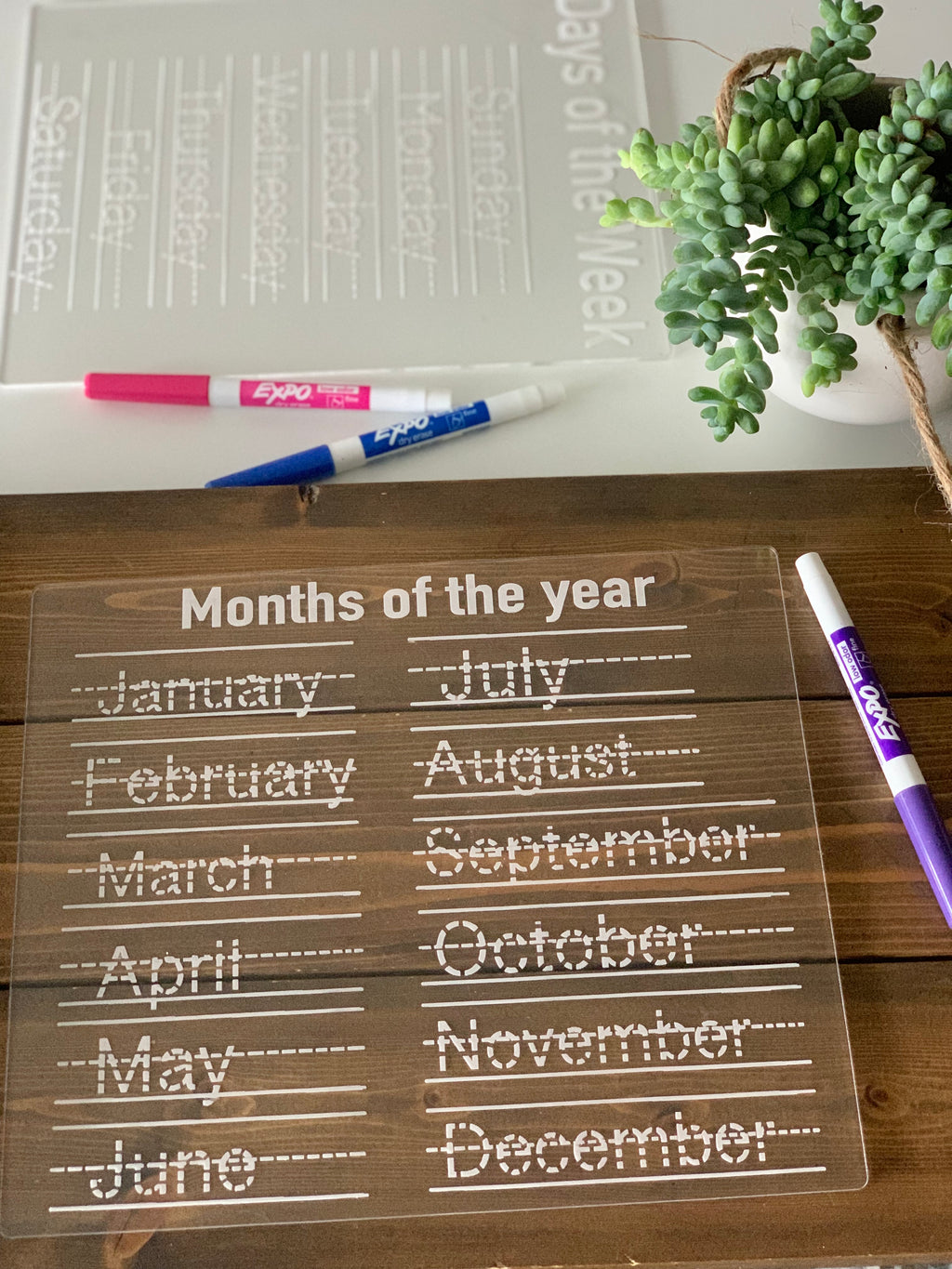 Clear acrylic dry erase board with months of the year in dotted handwriting for tracing and writing practice