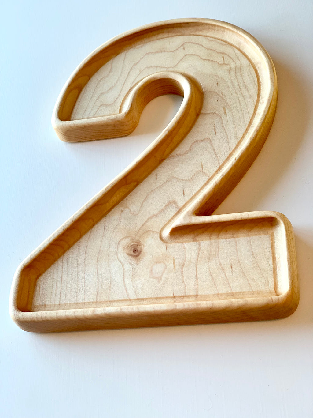 Large natural wooden number plate in the shape of digit 2 with smooth edges and visible wood grain texture on white background