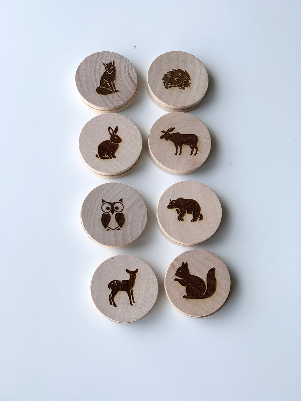 Wooden 2-inch discs with engraved woodland animal illustrations arranged in two neat vertical columns on white background