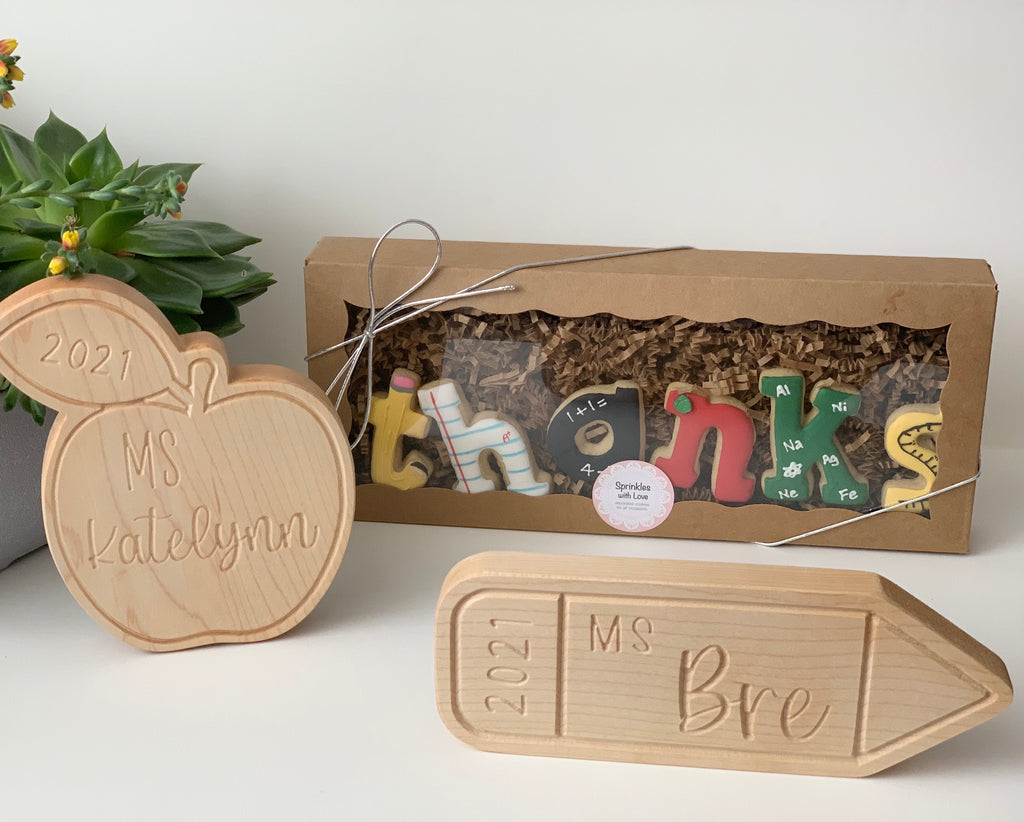 Natural wooden personalized teacher name plaques shaped like an apple and pencil with engraved names and year 2021
