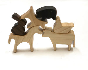 Natural wooden farm animal toy figurines stacked including horse, pig, rabbit, dog, cow, and chicken on white background
