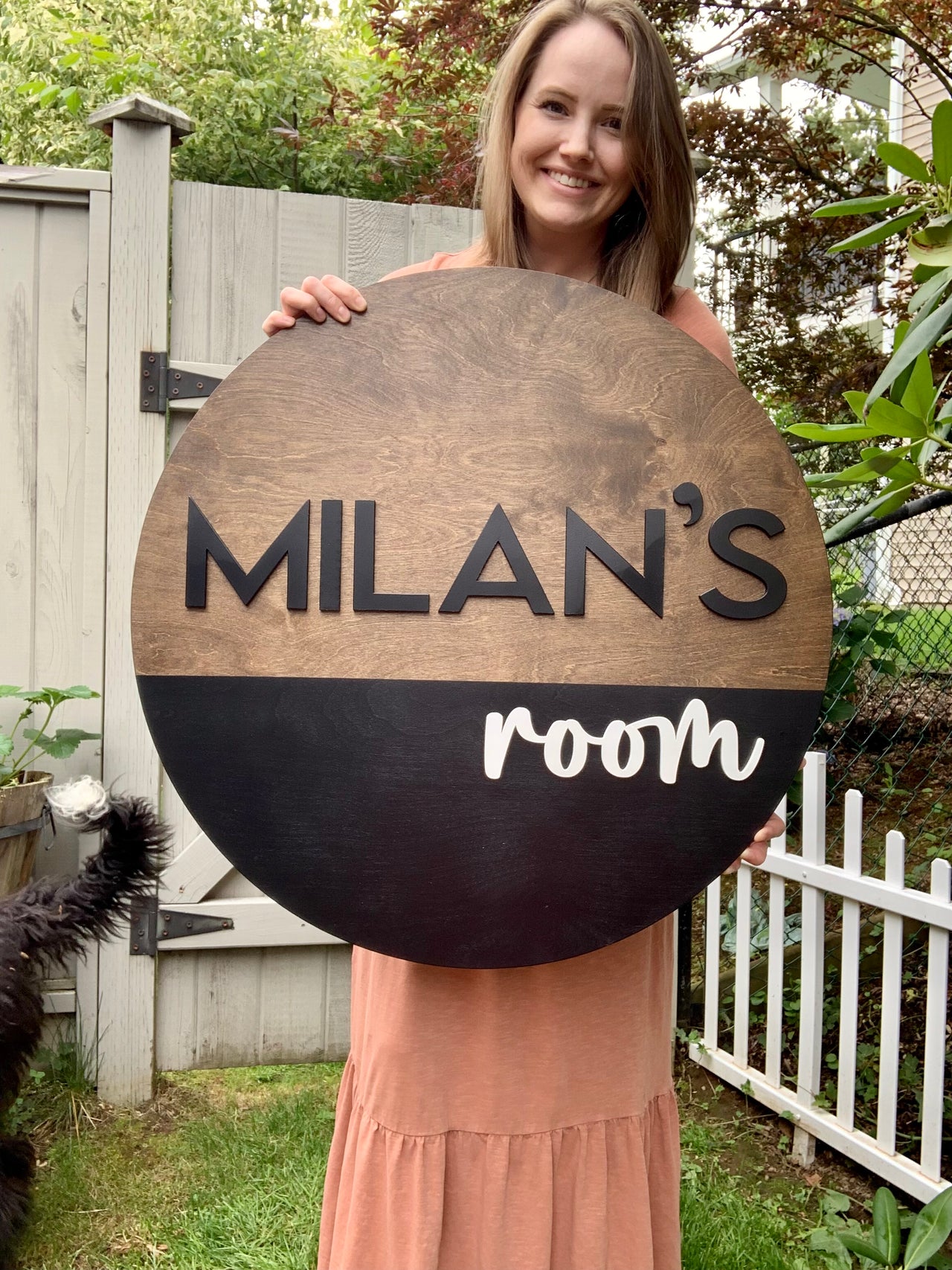 Round half painted wooden name sign with black block letters and white cursive on natural and black wood background