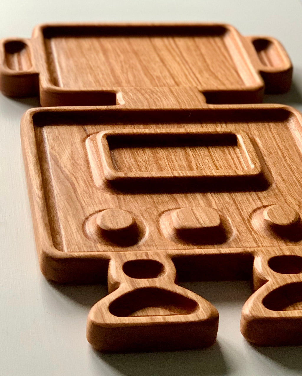 Wooden robot-shaped sensory tray with carved buttons and compartments on light surface
