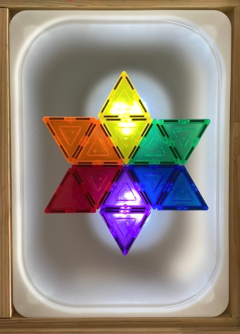 Frosted acrylic Flisat table top with colorful translucent magnetic triangles arranged in star shape on light table