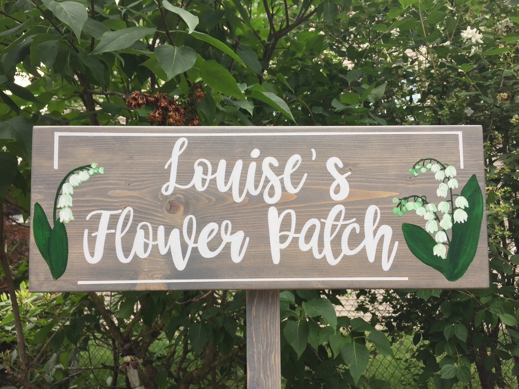 Large personalized wooden garden sign painted gray with white cursive letters and lily of the valley floral illustrations
