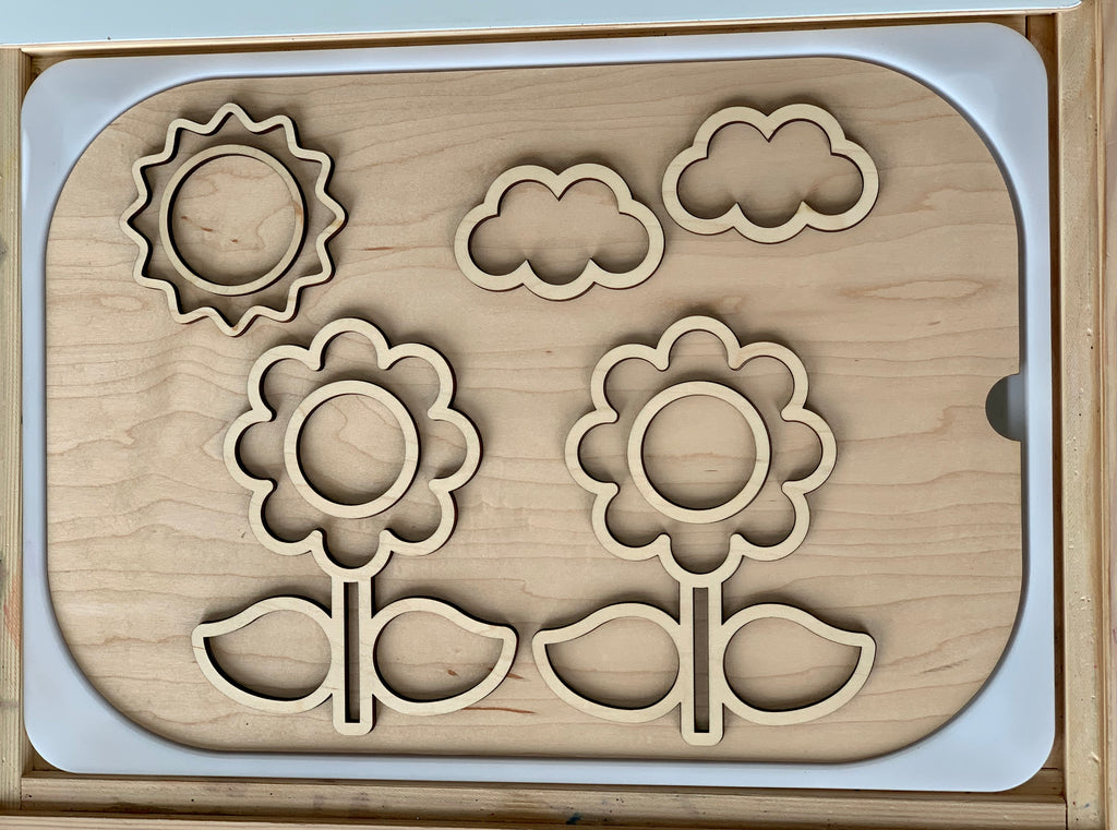 Wooden flower-themed fillable Flisat table insert with sun and cloud cutouts on light wood surface