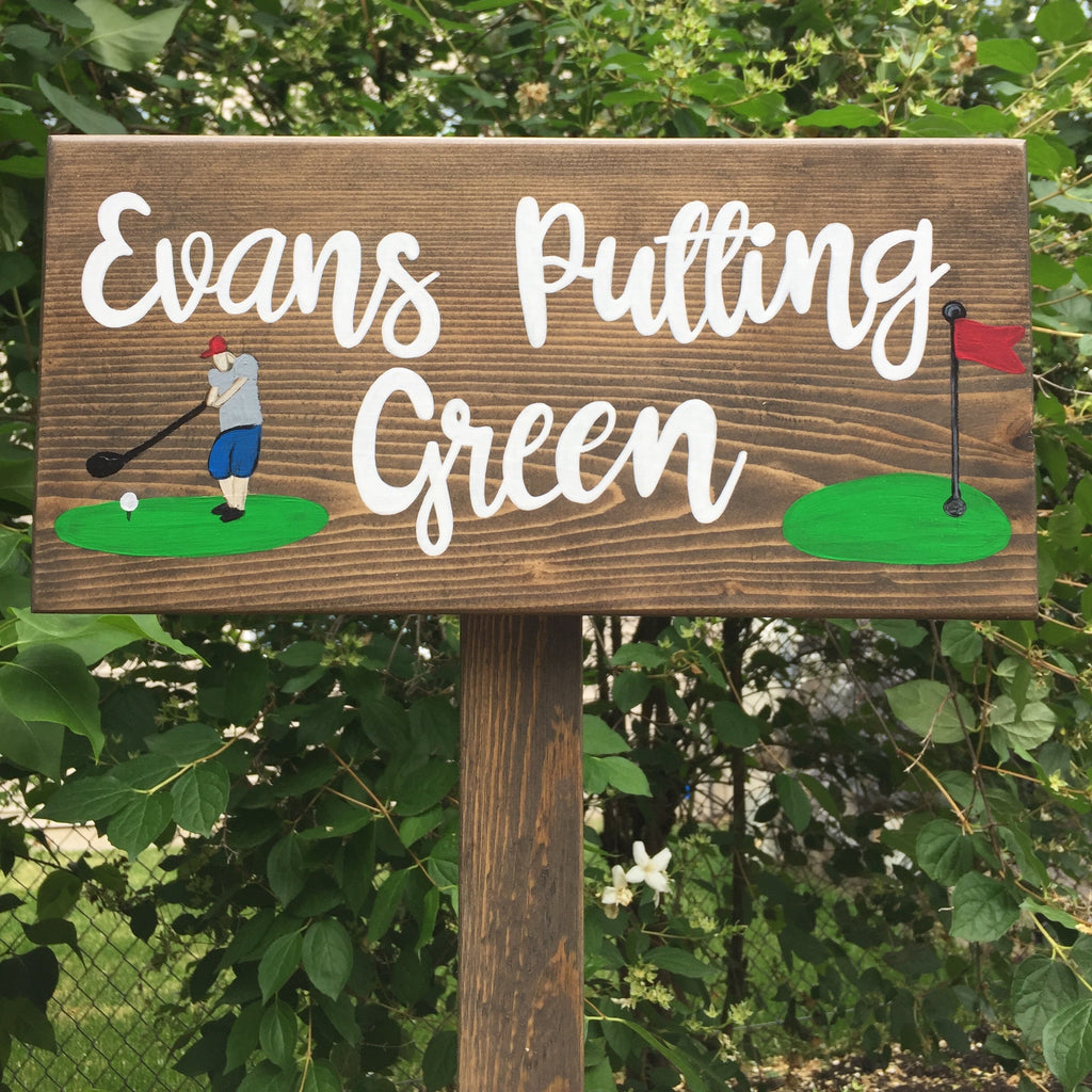 Custom wooden garden sign with white cursive letters and painted golfer and red flag illustrations on natural wood background