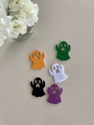 Set of 5 laser cut acrylic Halloween ghost shapes in orange, green glitter, white, black, and purple glitter on beige surface
