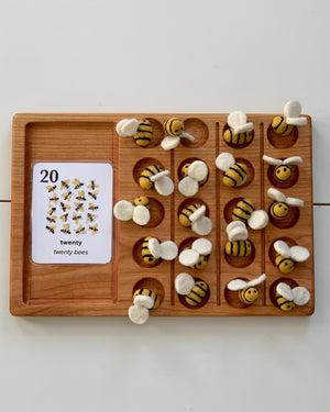 Wooden counting board with twenty felt bees featuring yellow and black stripes and white wings arranged in rows